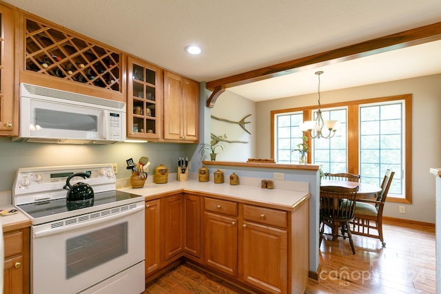 kitchen with pendant lighting, light countertops, glass insert cabinets, white appliances, and a peninsula