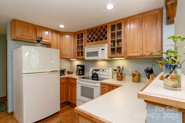 kitchen with wood-type flooring, white appliances, and kitchen peninsula