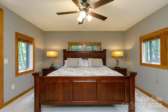 bedroom with ceiling fan, multiple windows, baseboards, and light colored carpet