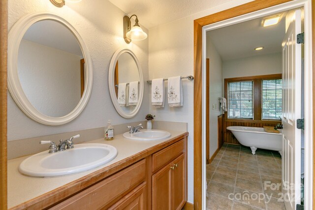 bathroom with double vanity, a washtub, and tile patterned flooring