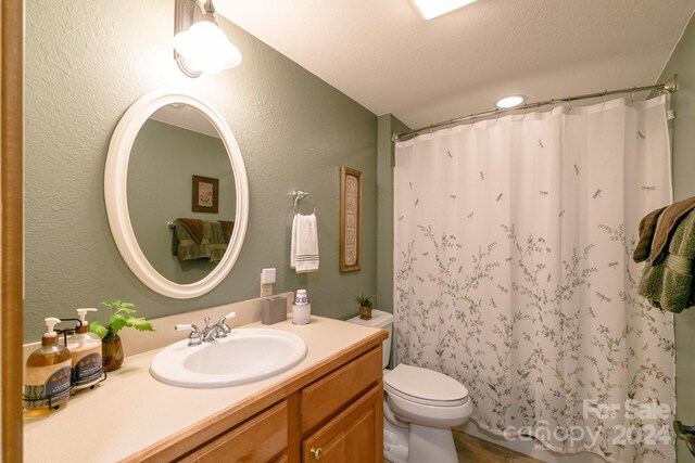 bathroom with toilet, vanity, and a textured ceiling