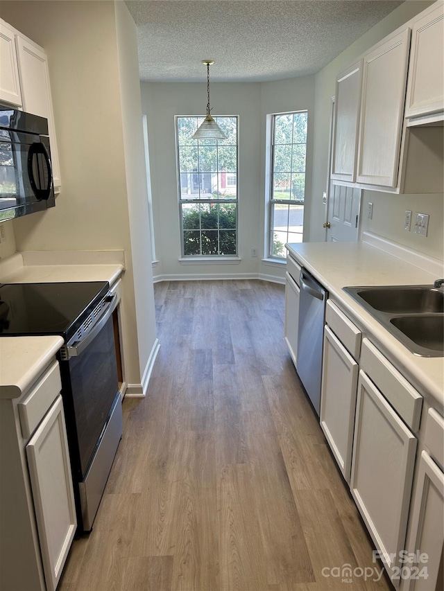 kitchen with stainless steel appliances, white cabinetry, hanging light fixtures, and light hardwood / wood-style flooring