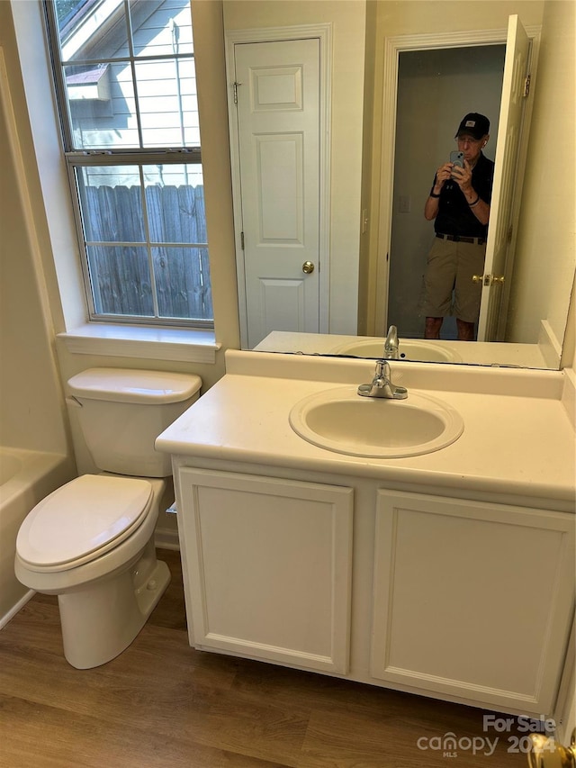 bathroom featuring a tub to relax in, vanity, wood-type flooring, and toilet