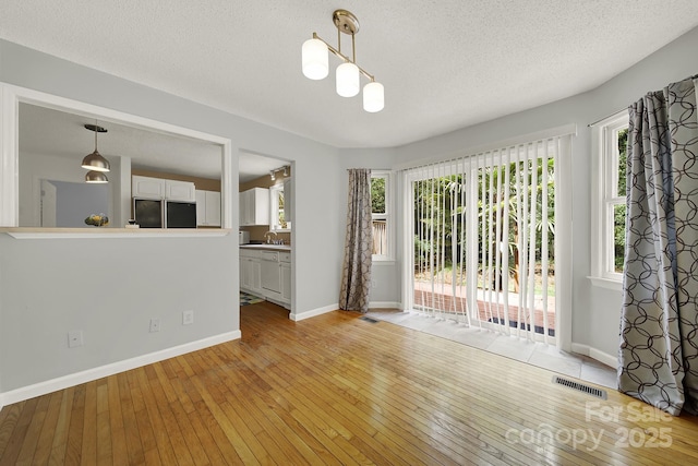 9143 Sadlers Ridge Rd, Fort Mill, SC 29707 - empty room with light wood-style floors, healthy amount of natural light, a textured ceiling, a sink, and baseboards