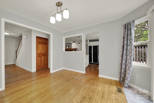 9143 Sadlers Ridge Rd, Fort Mill, SC 29707 - unfurnished room featuring light wood-type flooring, stairway, baseboards, and a chandelier