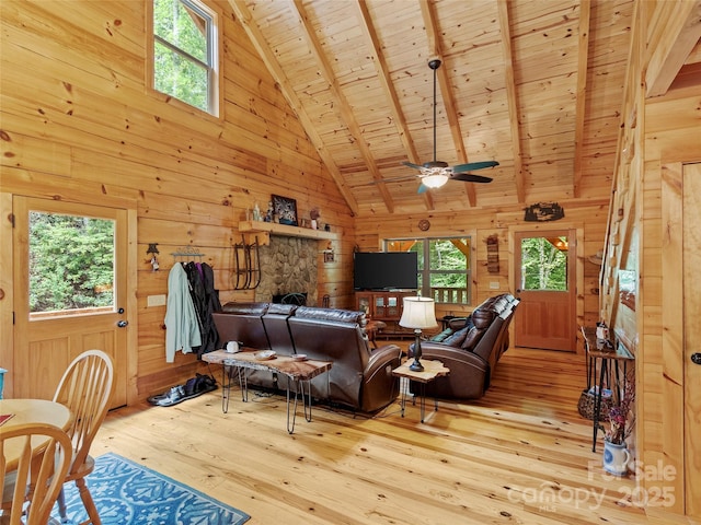 living room with a stone fireplace, light wood-type flooring, wooden ceiling, and wooden walls