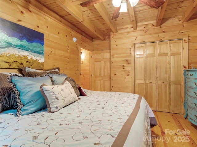 bedroom featuring beam ceiling, wood ceiling, light wood-type flooring, and wood walls