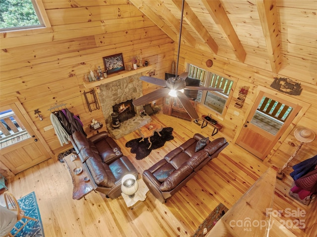 unfurnished living room featuring wood-type flooring, vaulted ceiling with beams, a fireplace, and wood walls