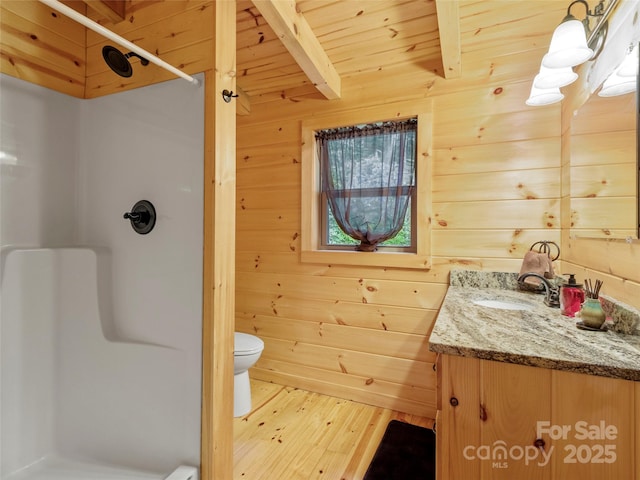 bathroom featuring walk in shower, toilet, vanity, wooden walls, and beamed ceiling