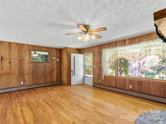 entrance foyer with ceiling fan, light hardwood / wood-style flooring, baseboard heating, and wooden walls