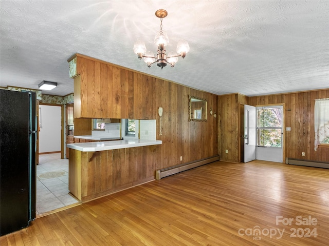 kitchen with light wood-type flooring, black refrigerator, kitchen peninsula, and a baseboard radiator