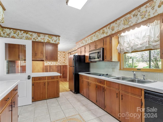 kitchen with sink, ornamental molding, light hardwood / wood-style flooring, a textured ceiling, and black appliances