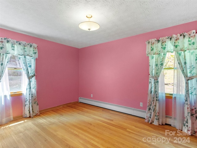 spare room with a textured ceiling, light hardwood / wood-style flooring, and a baseboard radiator