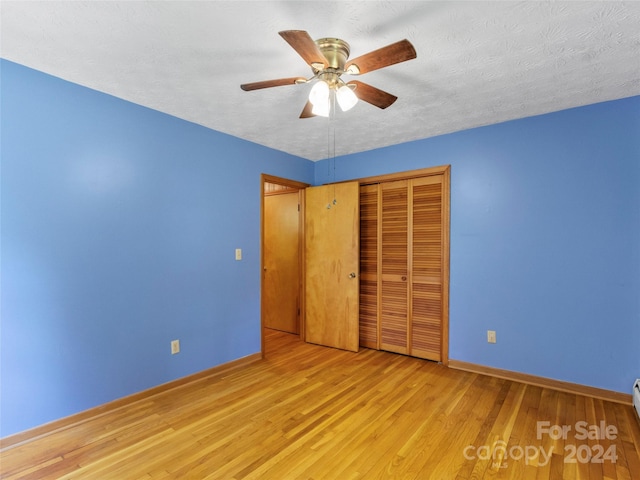 unfurnished bedroom featuring light wood-type flooring, ceiling fan, a closet, and a textured ceiling