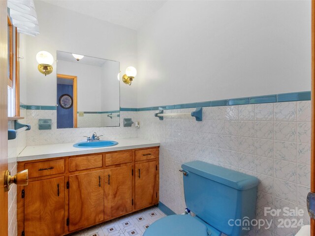 bathroom with tile walls, tile patterned flooring, vanity, and toilet