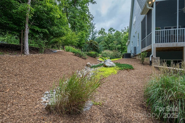 view of yard featuring a sunroom and central AC unit