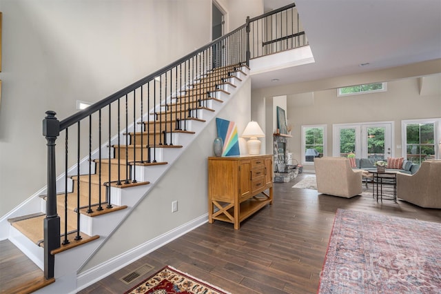 staircase featuring french doors, a towering ceiling, and hardwood / wood-style flooring