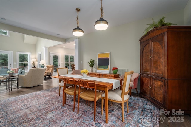 dining space with hardwood / wood-style floors and ornate columns