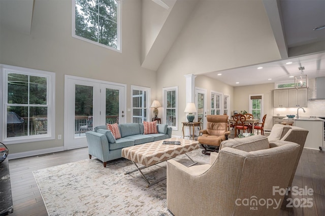 living room with a high ceiling, light wood-type flooring, french doors, and sink