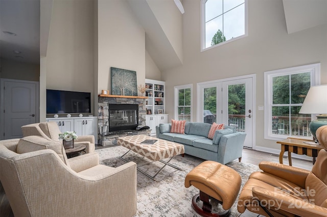 living room featuring a stone fireplace, a towering ceiling, and light wood-type flooring