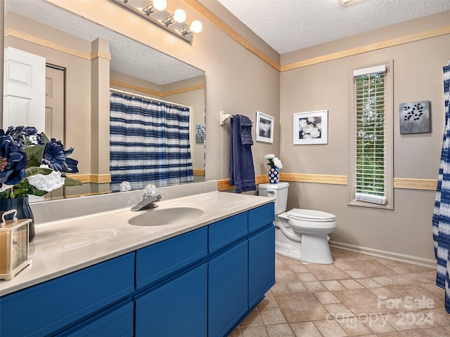 bathroom with vanity, toilet, and a textured ceiling