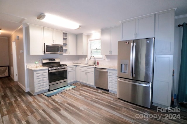 kitchen with stainless steel appliances, a sink, open shelves, light wood finished floors, and crown molding