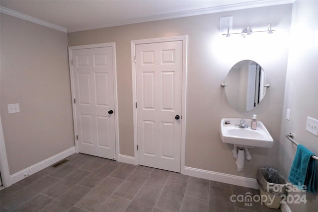 bathroom with visible vents, baseboards, wood tiled floor, crown molding, and a sink