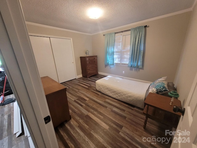 bedroom featuring a textured ceiling, ornamental molding, a closet, and wood finished floors