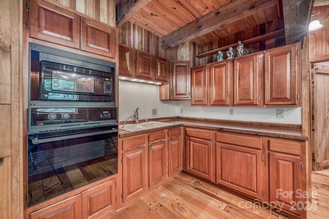 kitchen featuring sink, beamed ceiling, light wood-type flooring, and black appliances