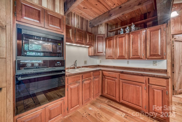 kitchen featuring a sink, brown cabinets, black appliances, light wood finished floors, and beamed ceiling