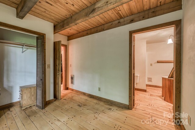 unfurnished bedroom featuring a closet, beamed ceiling, light hardwood / wood-style flooring, and wood ceiling