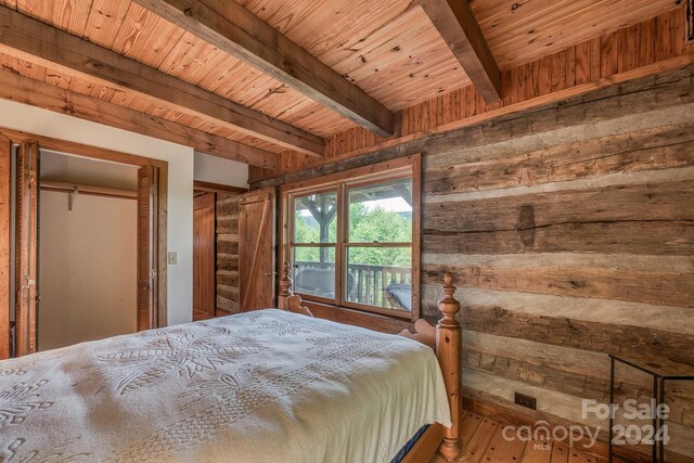 unfurnished bedroom with beam ceiling, wood-type flooring, wood walls, and wood ceiling