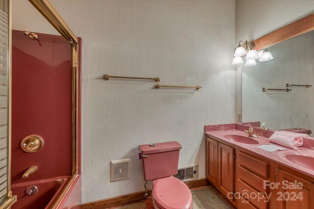 full bathroom featuring shower / bath combination with glass door, toilet, and double sink vanity