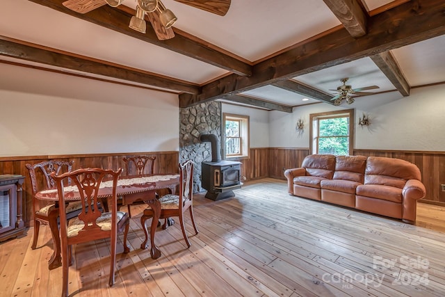 dining space featuring a wealth of natural light, light wood-type flooring, a wood stove, and a wainscoted wall