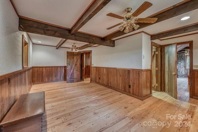 unfurnished room featuring a ceiling fan, wainscoting, beamed ceiling, and light wood finished floors