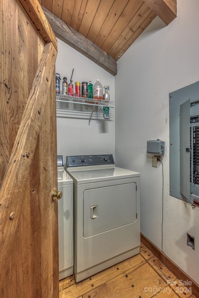 washroom featuring washing machine and clothes dryer, electric panel, light wood-type flooring, and wooden ceiling