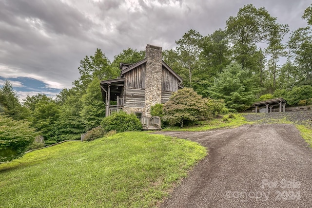 view of property exterior with stone siding, a chimney, and a lawn