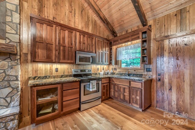 kitchen with beamed ceiling, appliances with stainless steel finishes, sink, light wood-type flooring, and dark stone countertops