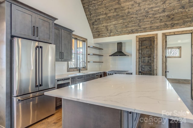 kitchen featuring vaulted ceiling, plenty of natural light, wall chimney range hood, and appliances with stainless steel finishes