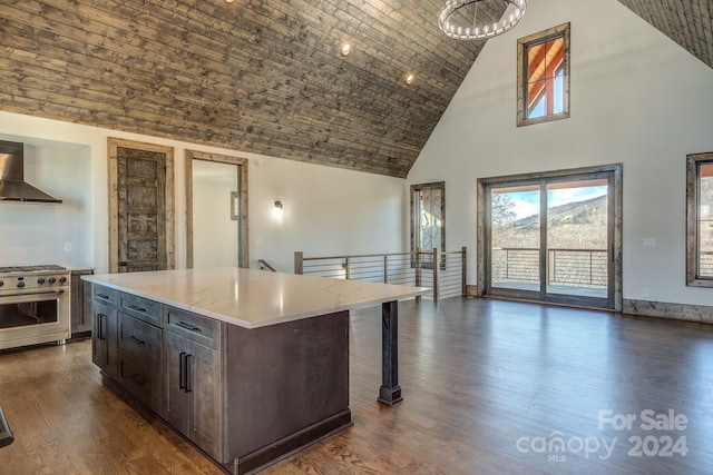 kitchen featuring wall chimney exhaust hood, high end stove, high vaulted ceiling, dark hardwood / wood-style floors, and a kitchen island