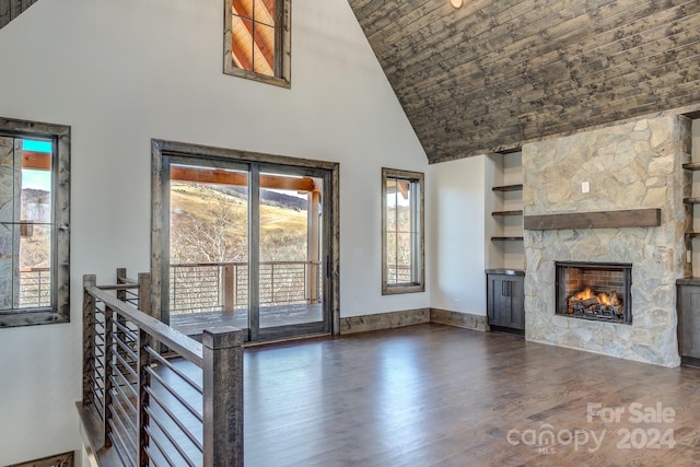 unfurnished living room featuring a stone fireplace, dark hardwood / wood-style flooring, and high vaulted ceiling