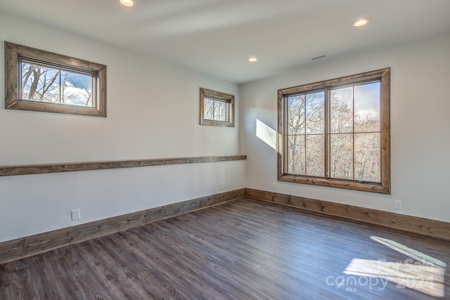 empty room with dark wood-type flooring and a healthy amount of sunlight