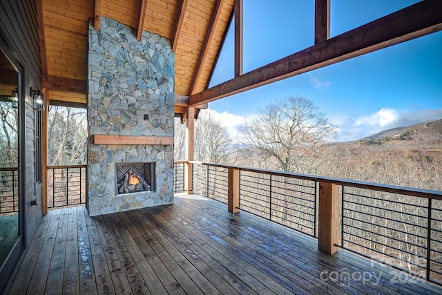 wooden terrace with an outdoor stone fireplace