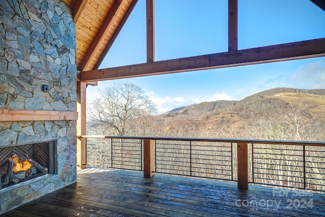 wooden deck with an outdoor stone fireplace and a mountain view