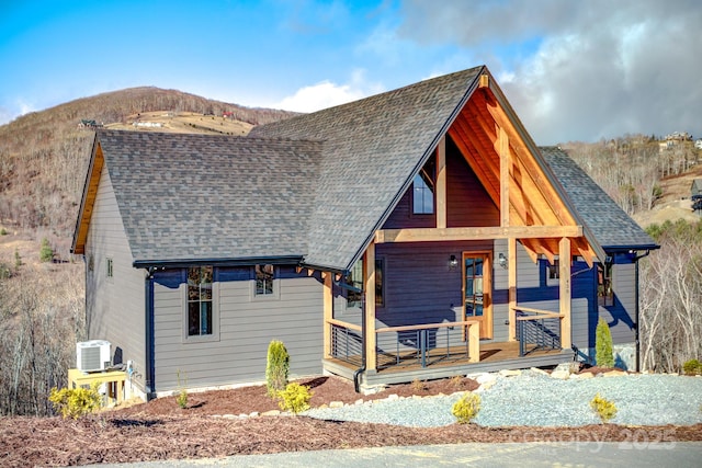 view of front of property with a porch, a mountain view, a shingled roof, and central AC unit