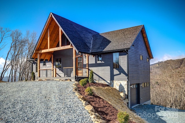 view of front of home with an attached garage, a shingled roof, and a porch