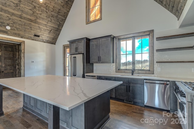 kitchen with light stone counters, high end appliances, a sink, and a center island