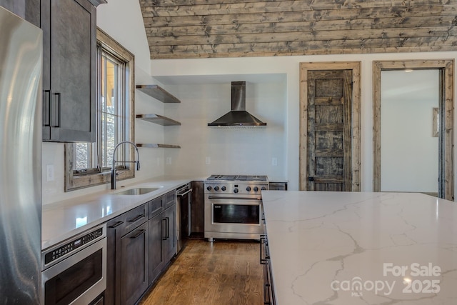 kitchen featuring light stone counters, open shelves, appliances with stainless steel finishes, a sink, and wall chimney exhaust hood