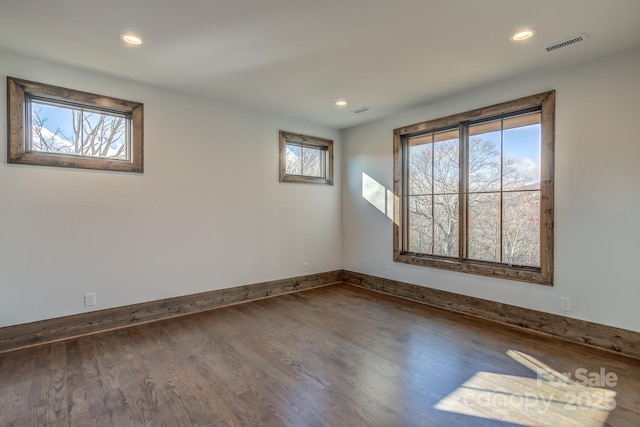 unfurnished room with baseboards, wood finished floors, visible vents, and recessed lighting