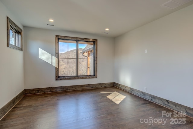 empty room with baseboards, visible vents, dark wood finished floors, and recessed lighting